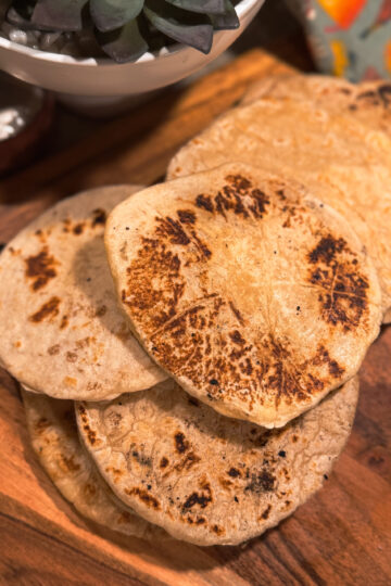 a stack of tortillas on a wooden board