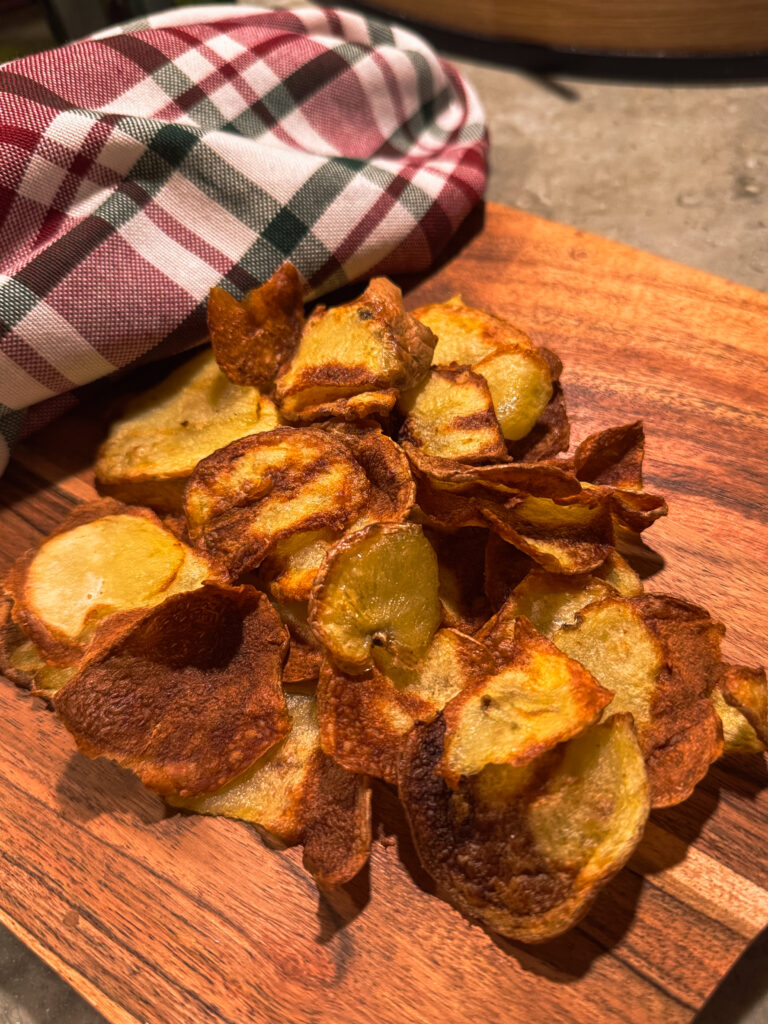 a pile of potato chips on a wooden board
